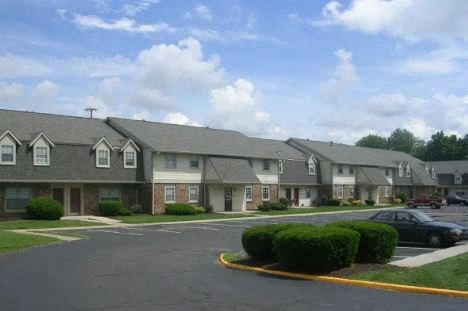 a row of apartment buildings with cars parked in a parking lot