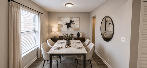A dining room with a table set for two and a large mirror on the wall.