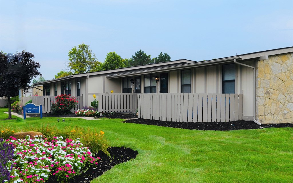 a white building with a white fence and flowers in front of it