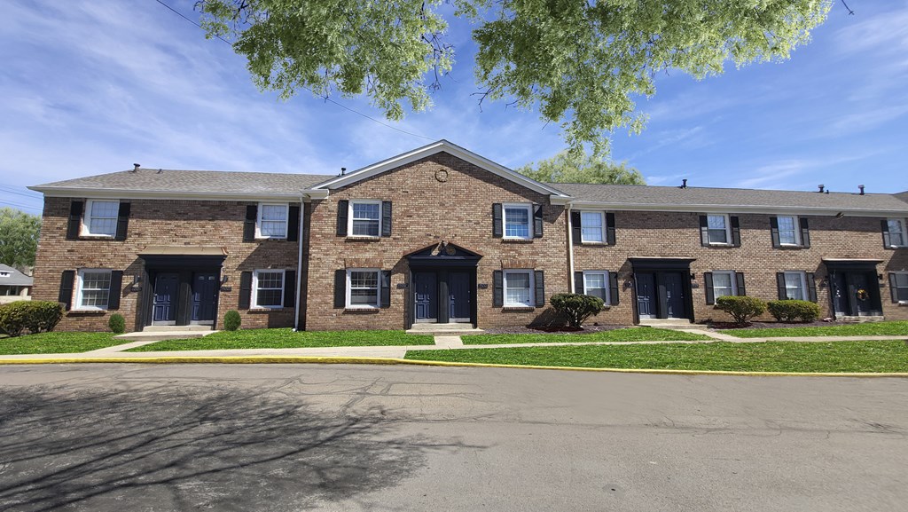 Apartment building with blue doors and windows under a clear sky.