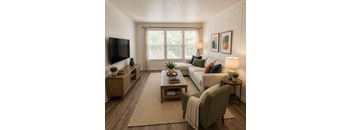 A living room with a white couch, a green armchair, a wooden coffee table, and a flat-screen TV mounted on the wall.