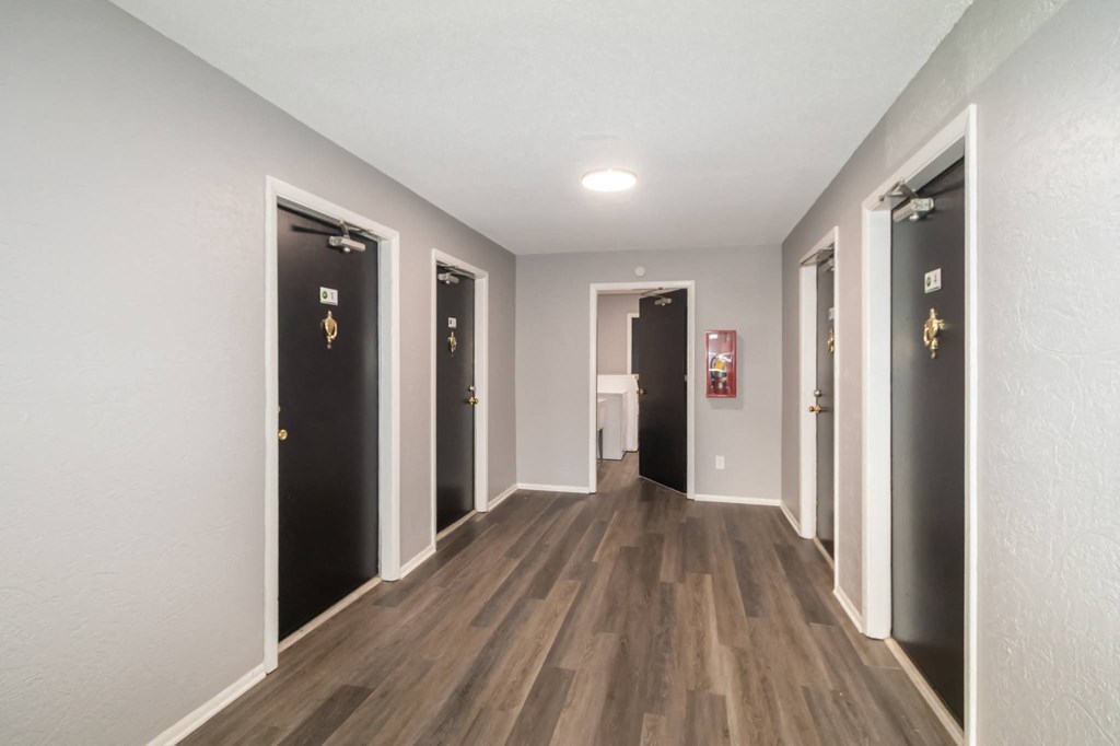 a long hallway with doors to different rooms and bathrooms