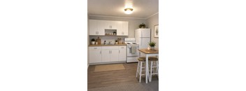 A kitchen with white appliances and wooden floors.