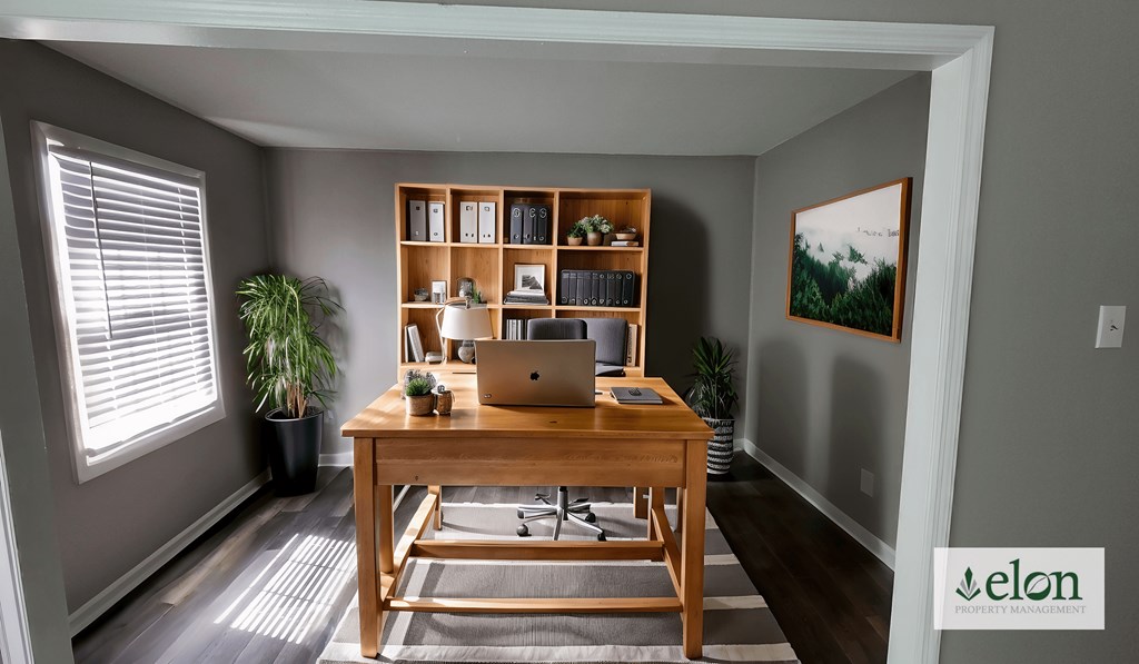 A room with a desk, laptop, and a potted plant.