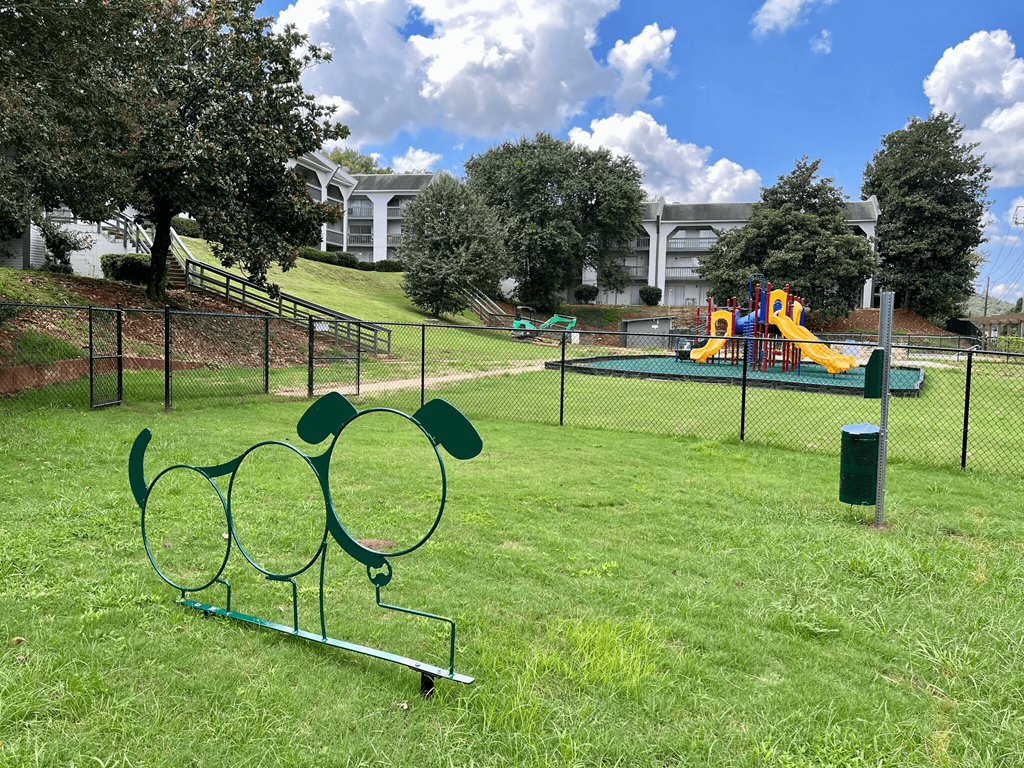 A playground with a slide and a green trash can.
