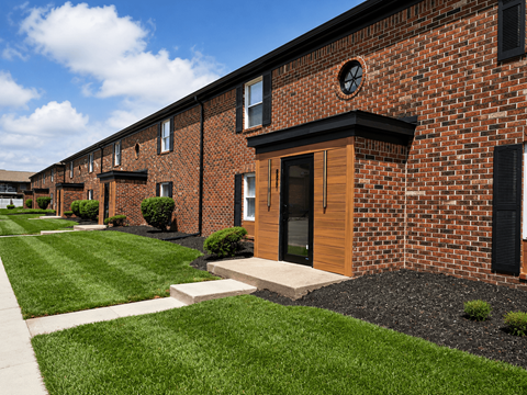 A row of red brick houses with green lawns in front.