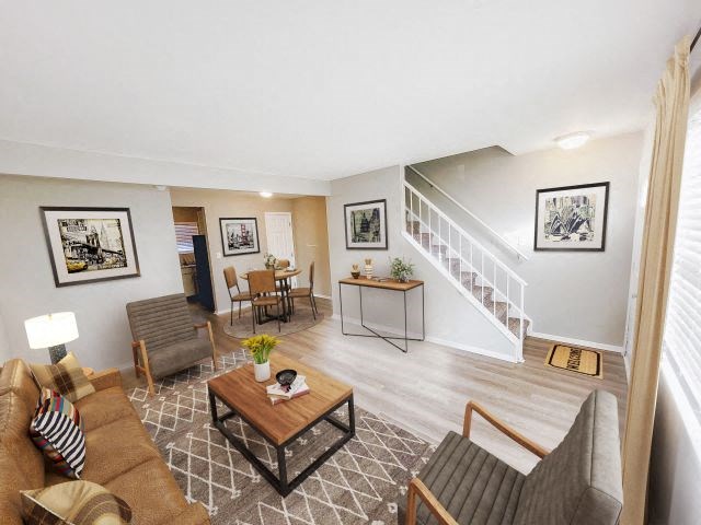 Living room with a couch and two chairs next to the dining area in a townhouse. 