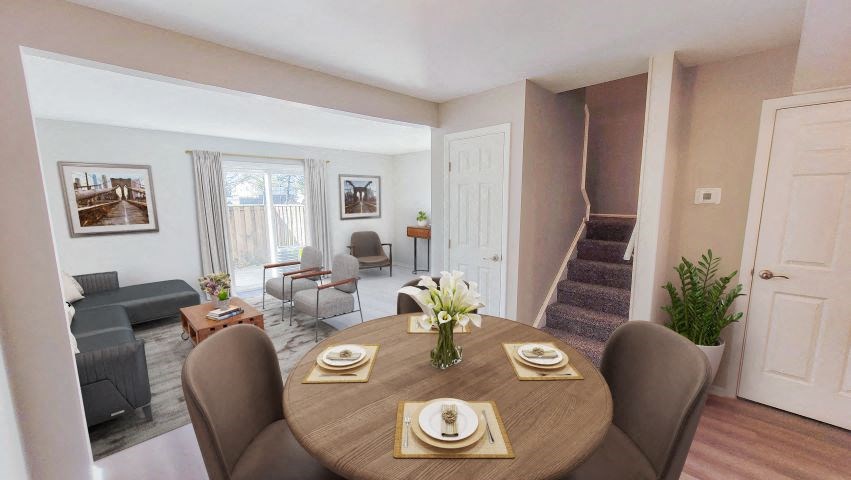 Circular dining table in front of the stairs while next to the living room area with sliding glass doors. 