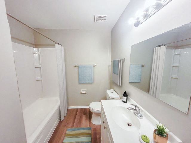 Bathroom with a large mirror, a bathtub, a toilet, and a sink with white countertops. 