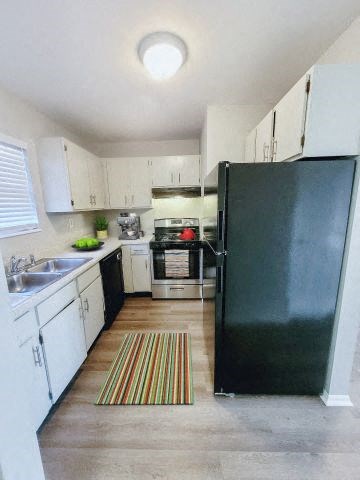 Kitchen area with a fridge, stovetop oven, dishwasher, and white cabinets. 