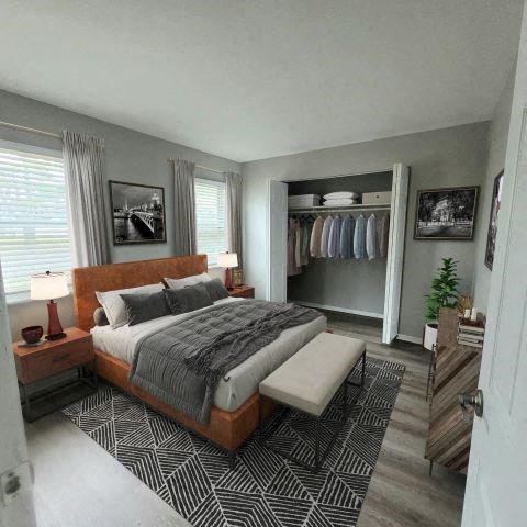 Bedroom with a bed in between two windows and a large closet on the side. 