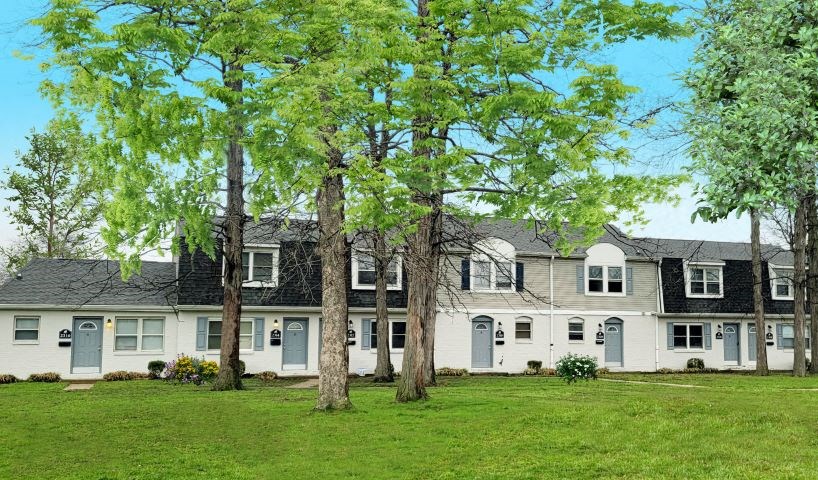 Exterior of townhomes with a large front yard and several trees. 