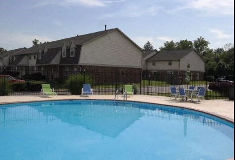 a swimming pool with chairs and a house in the background