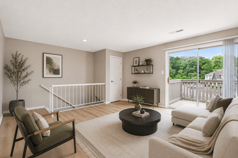 A living room with a white couch, a coffee table, and a tree.
