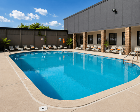 A large swimming pool with lounge chairs and a building in the background.