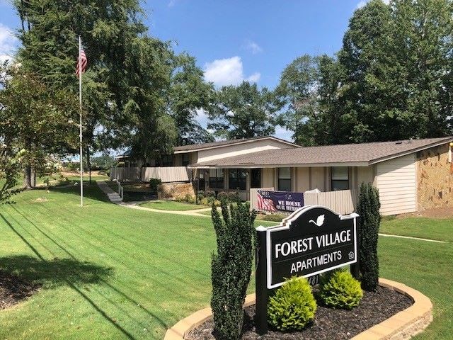 a house with a forest village apartments sign