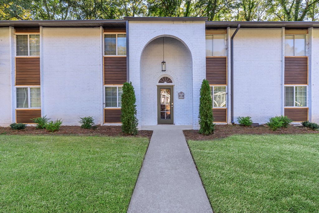 the front of a building with a sidewalk and grass