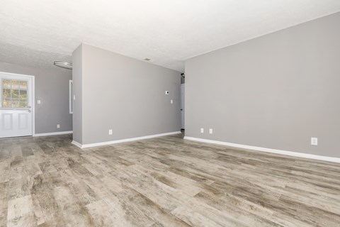 the living room and dining room of an empty house with wood flooring