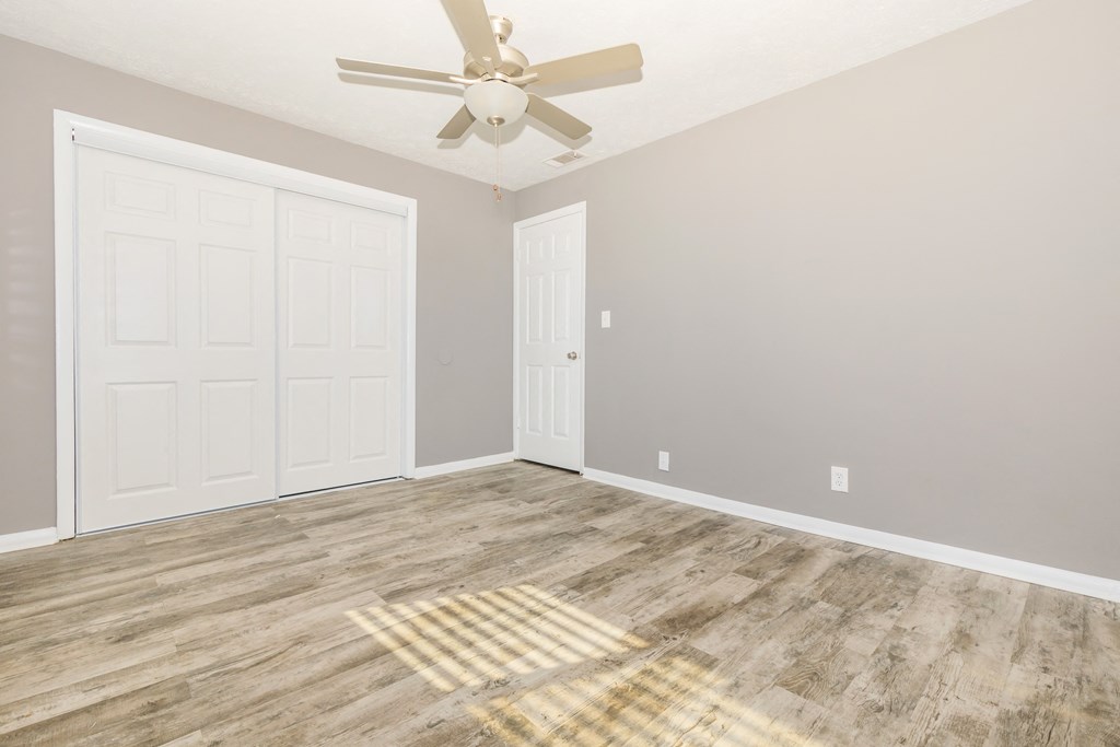 an empty room with a ceiling fan and a closet
