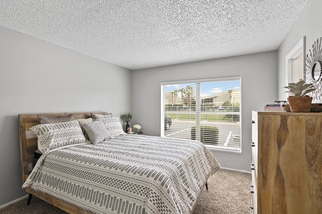 an empty bedroom with a bed and a large window