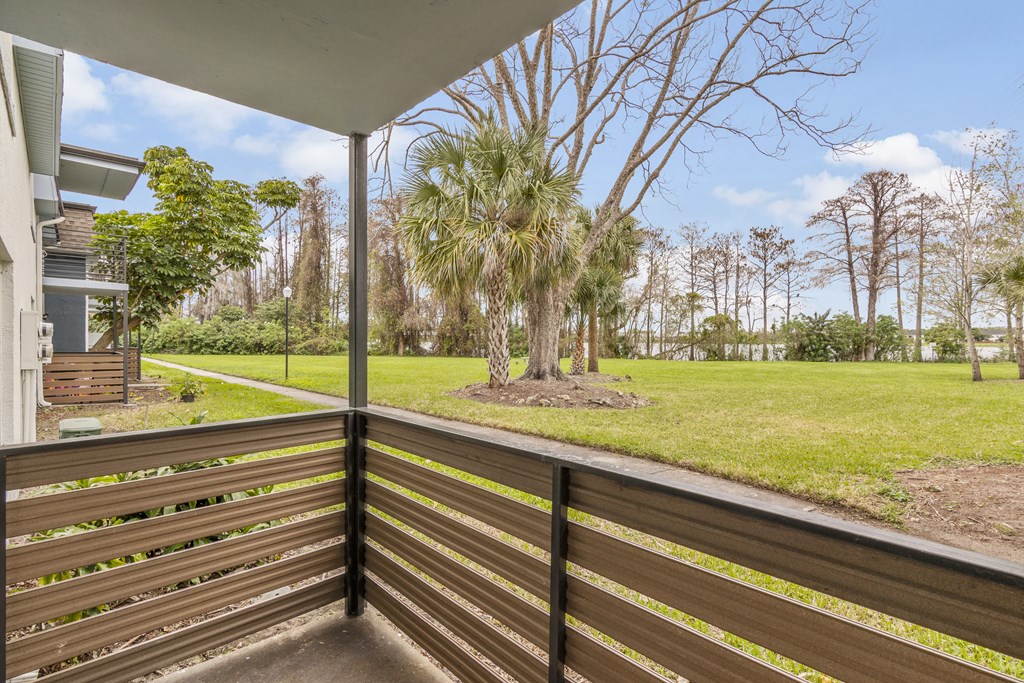 the view from the porch of a house with a yard and palm trees