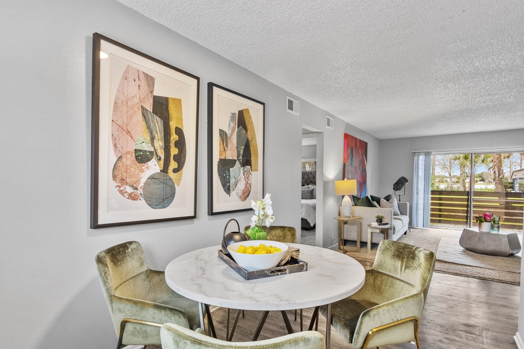 a living room with a table and chairs and paintings on the wall