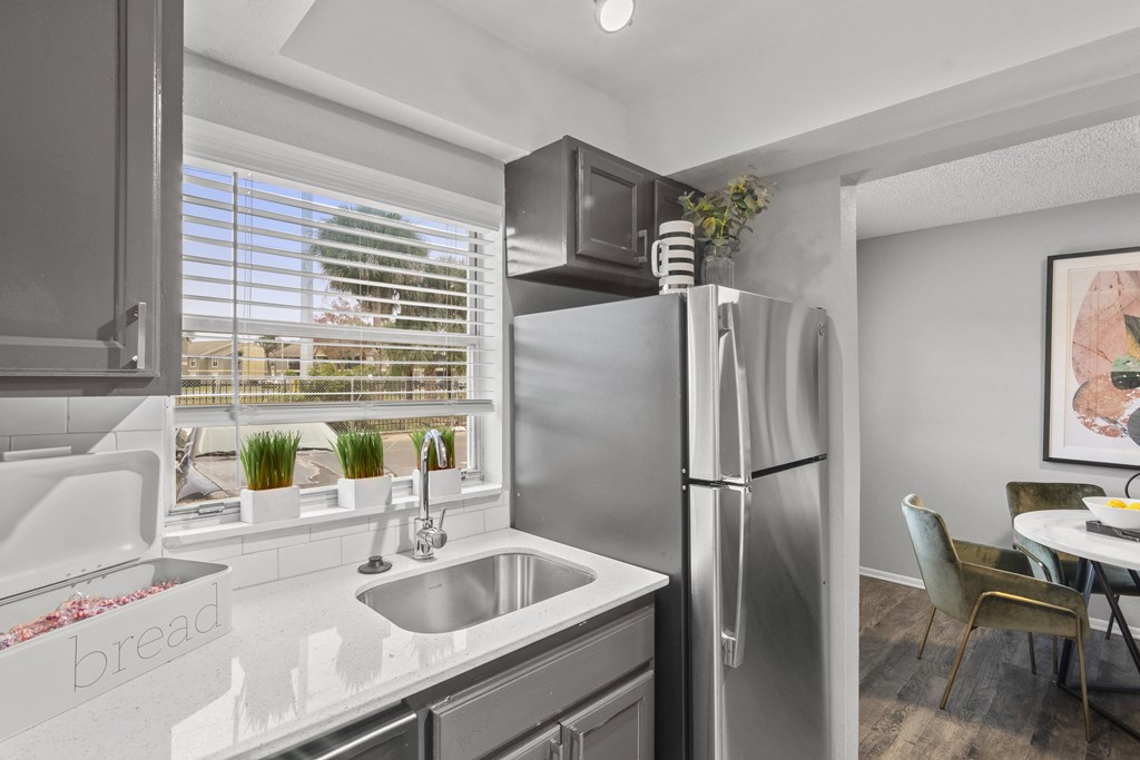 a kitchen with stainless steel refrigerator and sink and a window