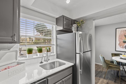 a kitchen with stainless steel refrigerator and sink and a window