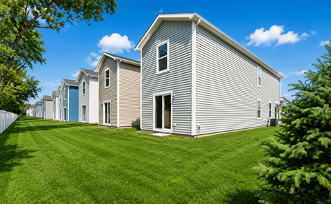 A row of houses with green lawns in front.