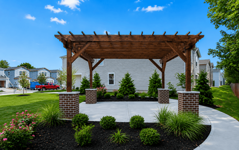 A wooden pergola is over a landscaped area.