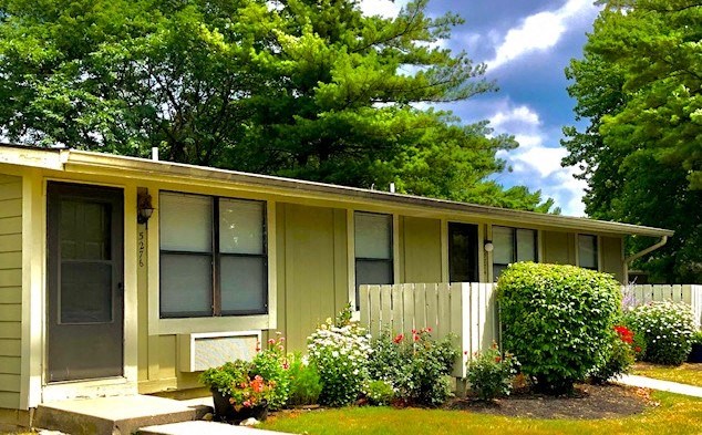 a yellow house with a porch and some flowers