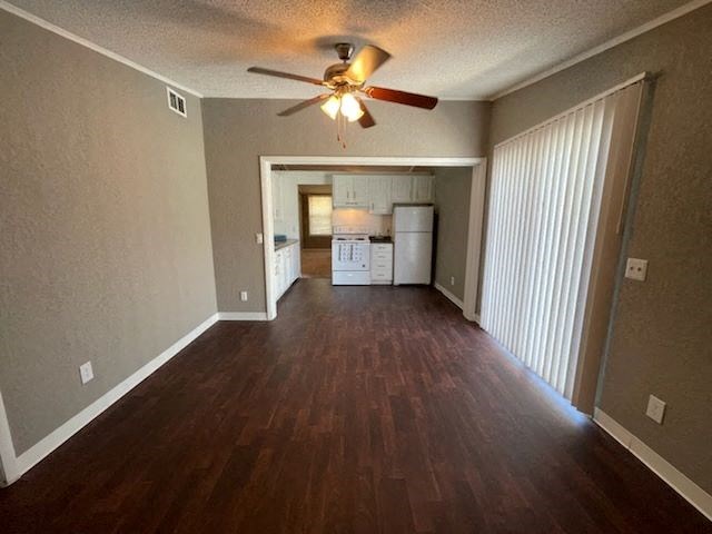 an empty living room with a ceiling fan and a kitchen