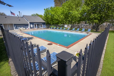 a swimming pool with chairs around it in front of a house