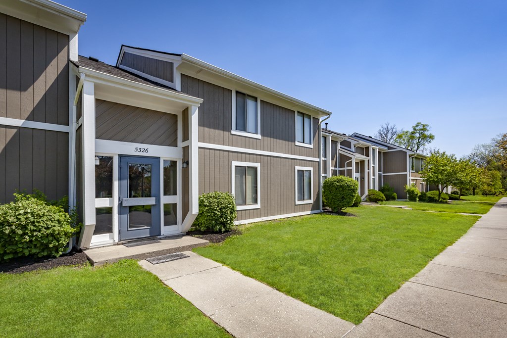 a row of townhomes with a sidewalk and grass
