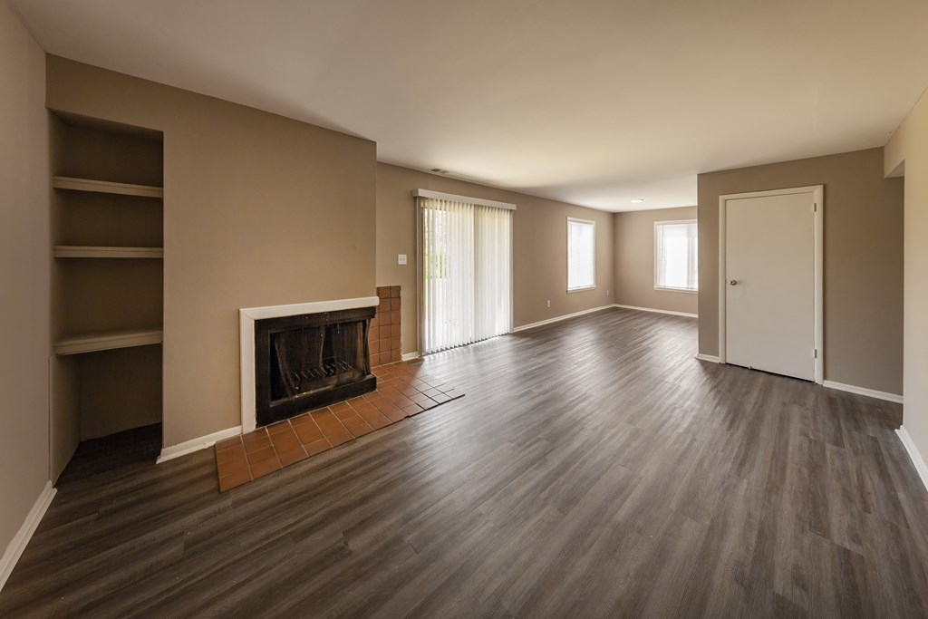 an empty living room with a fireplace and wooden floors
