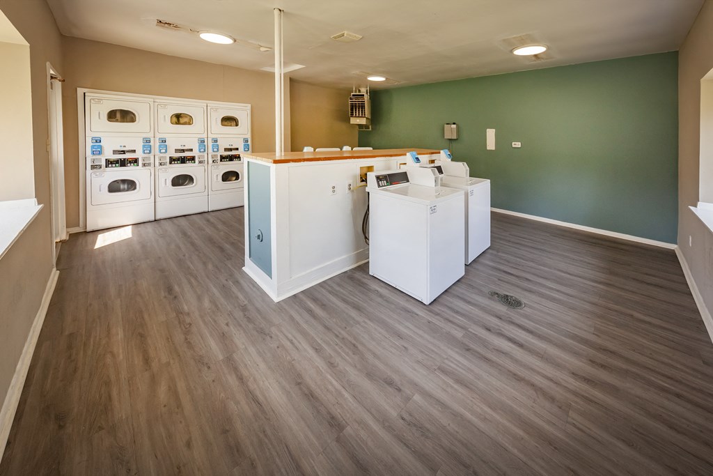 an empty laundry room with washer and dryers and a green wall and wood