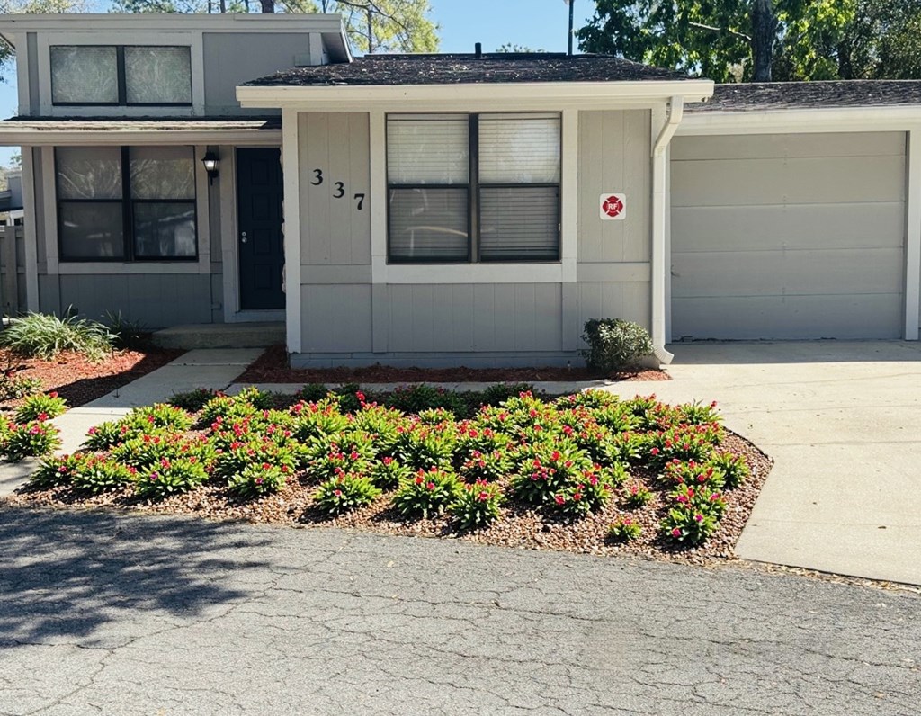 A grey house with a red and white sign on the garage door.