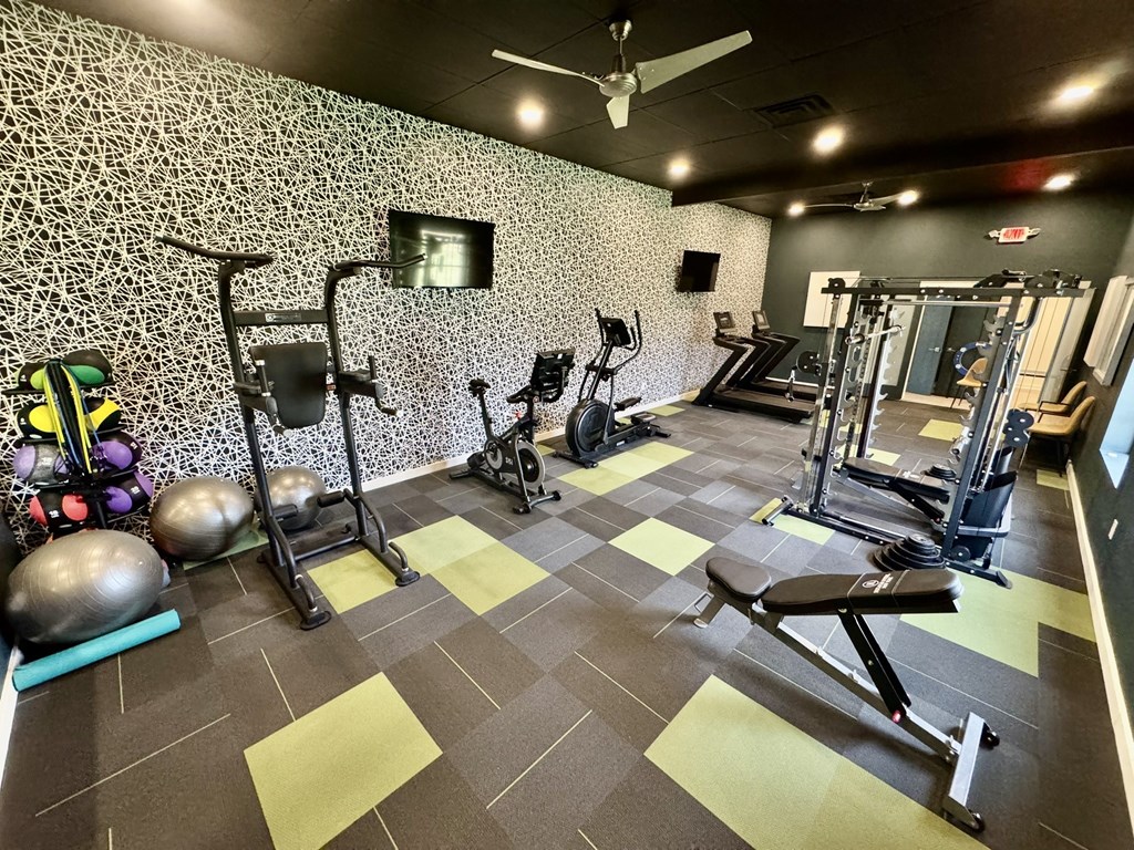 A gym with a variety of equipment including weights and a bench press. at Townhomes at 28th, Columbus, IN