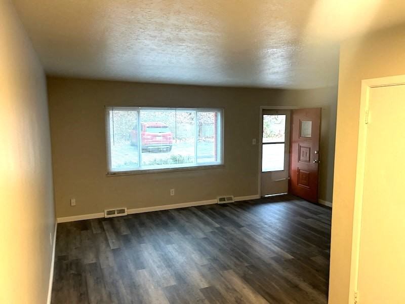 an empty living room with wood floors and a window