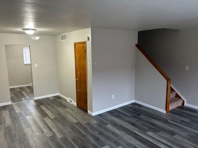 a empty living room with a wooden floor and a staircase