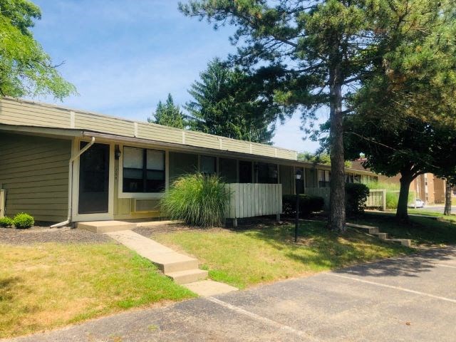 a green house with a tree in front of it
