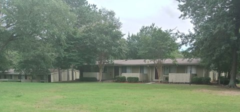 a house with a yard and trees in front of it