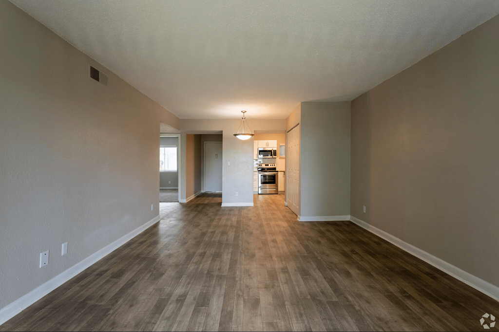 A long, empty hallway with wood flooring and white walls.