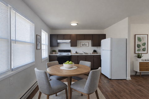 A kitchen with a table and chairs in the foreground and a refrigerator in the background.