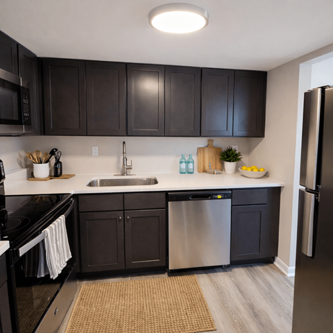 A modern kitchen with dark brown cabinets and stainless steel appliances.