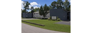 A building with the name "Village" on it is surrounded by trees and grass.