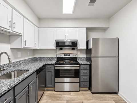 A kitchen with a stainless steel refrigerator and a black and white counter.