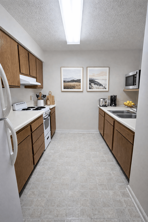 A kitchen with a white fridge, white stove, and white countertops.