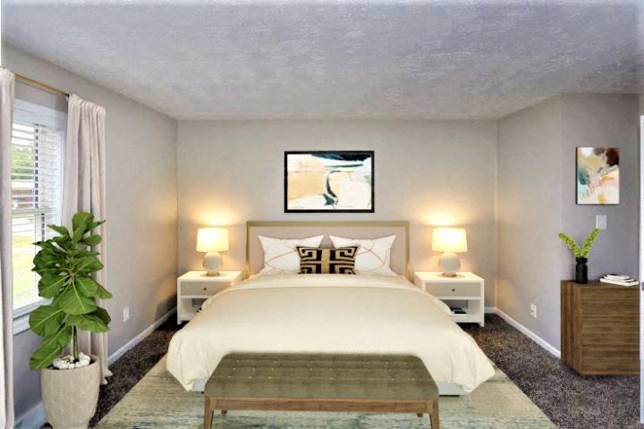 Carpeted bedroom with a bed in between two night stands and a window.  