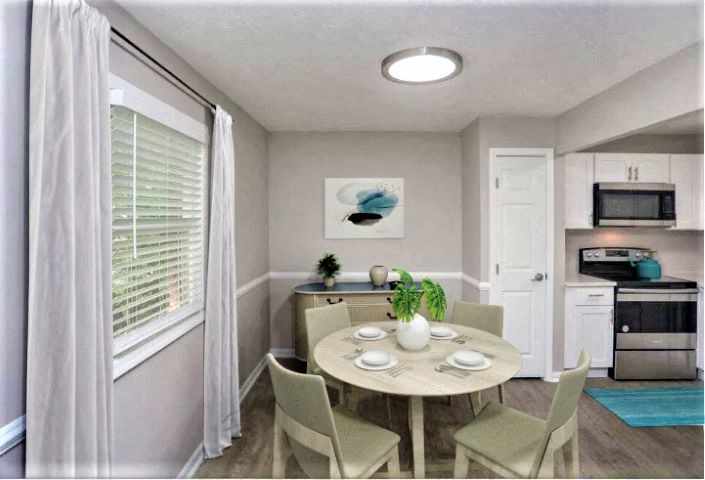Dining area with a circular table and 4 chairs in between the kitchen and a window.
